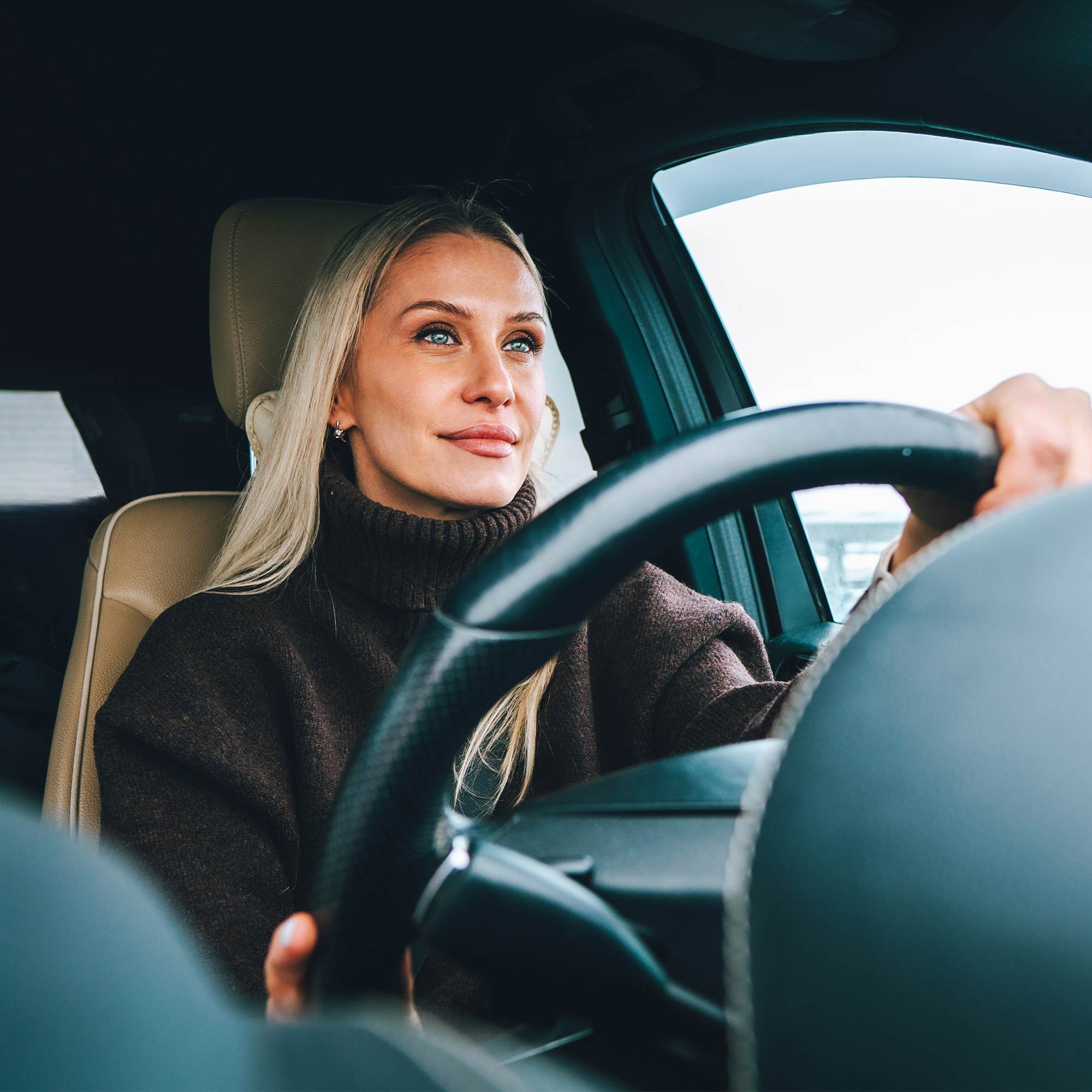 A man and woman smile at the salesman as they sit in a brand new red car.