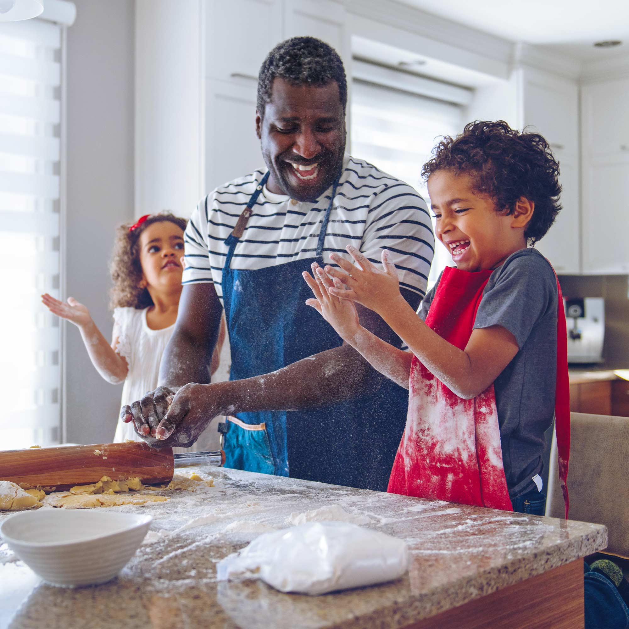 A man wears an apron as he's baking desserts with his two children.