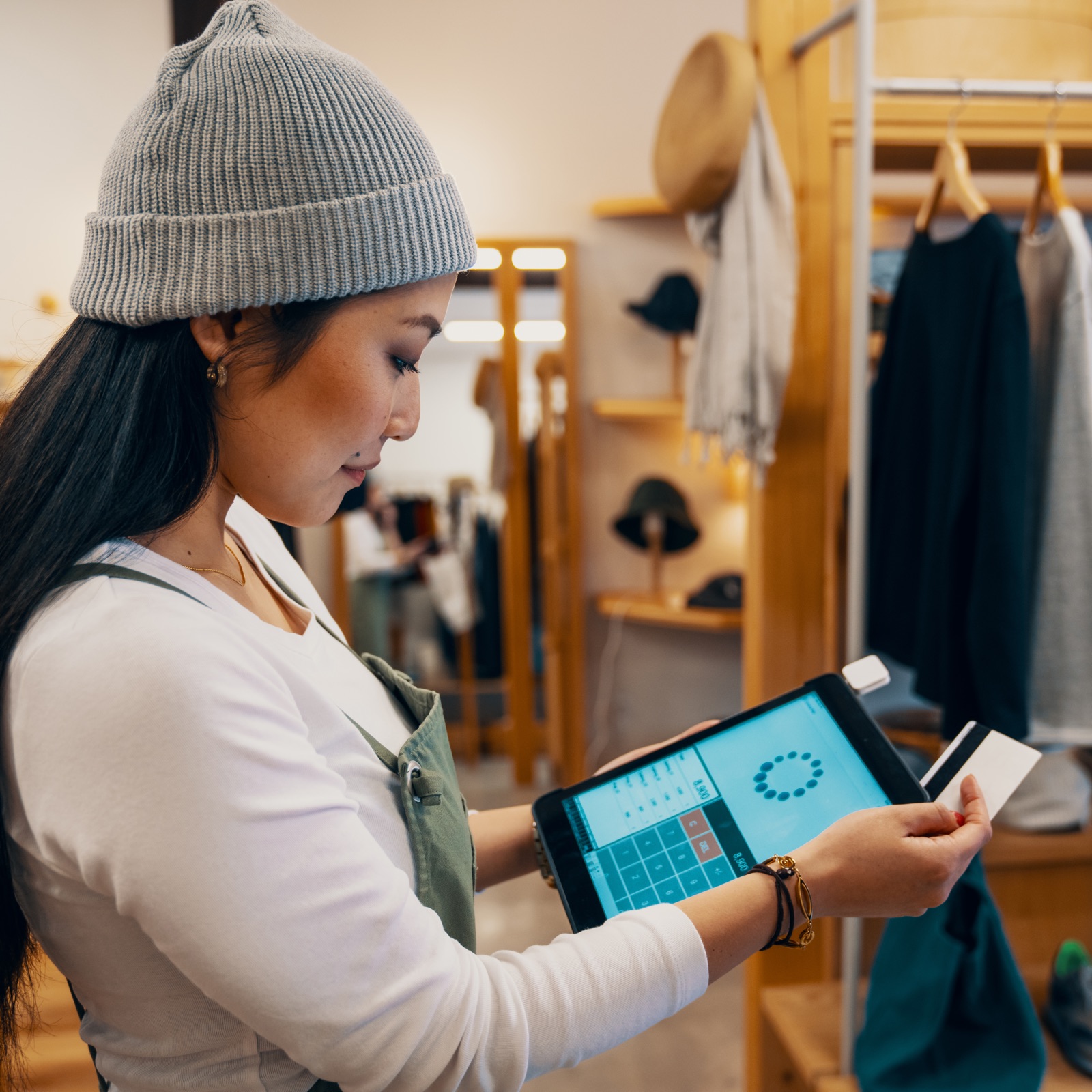 A woman in a clothing store pays for something digitally with her debit card.