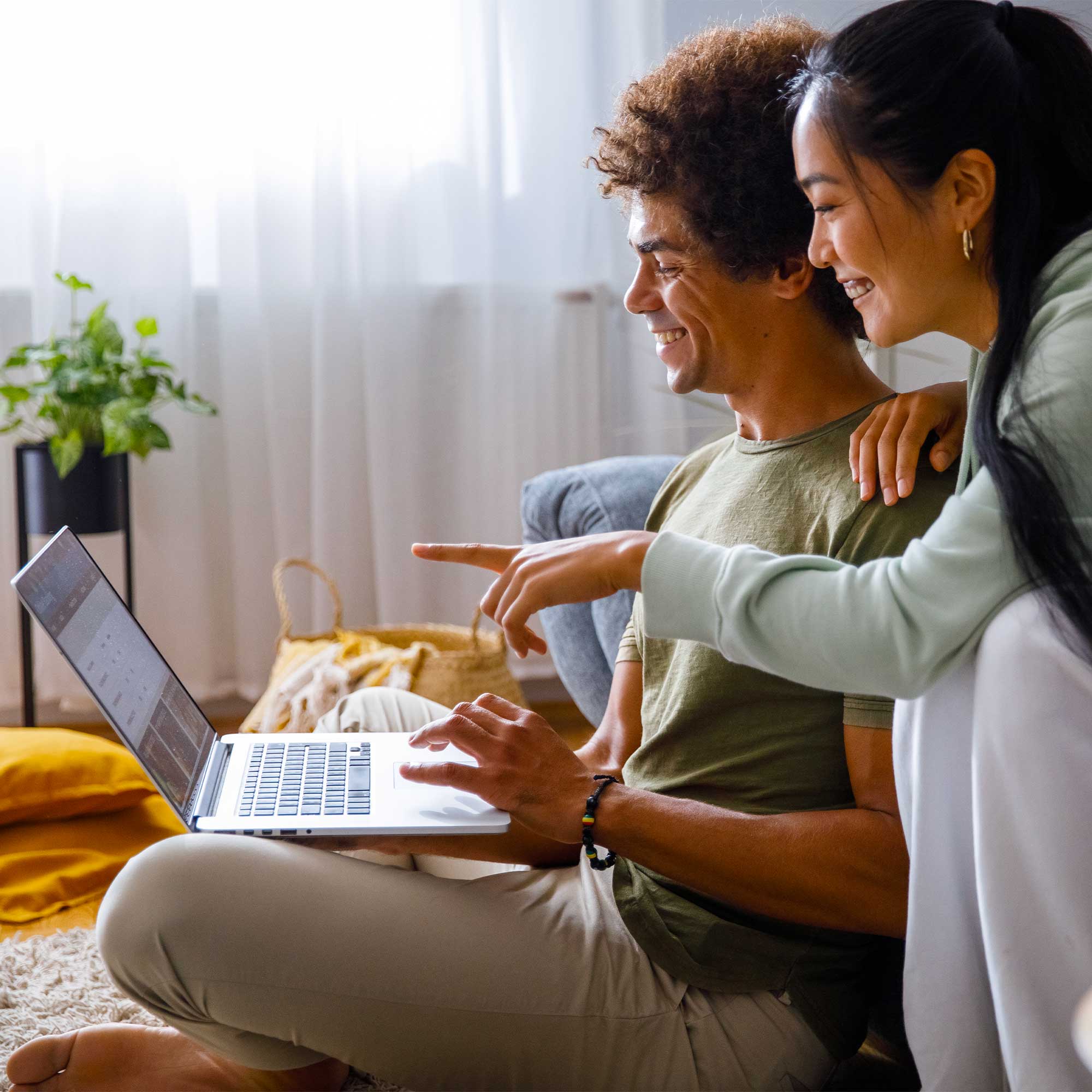A woman peers over her husbands shoulder as she points to the screen of the computer.