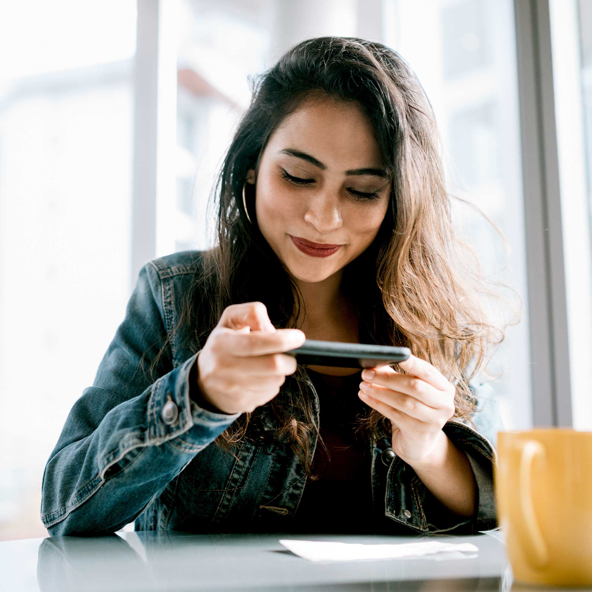 A woman sits at a table and uses her phone to take a picture of her check.