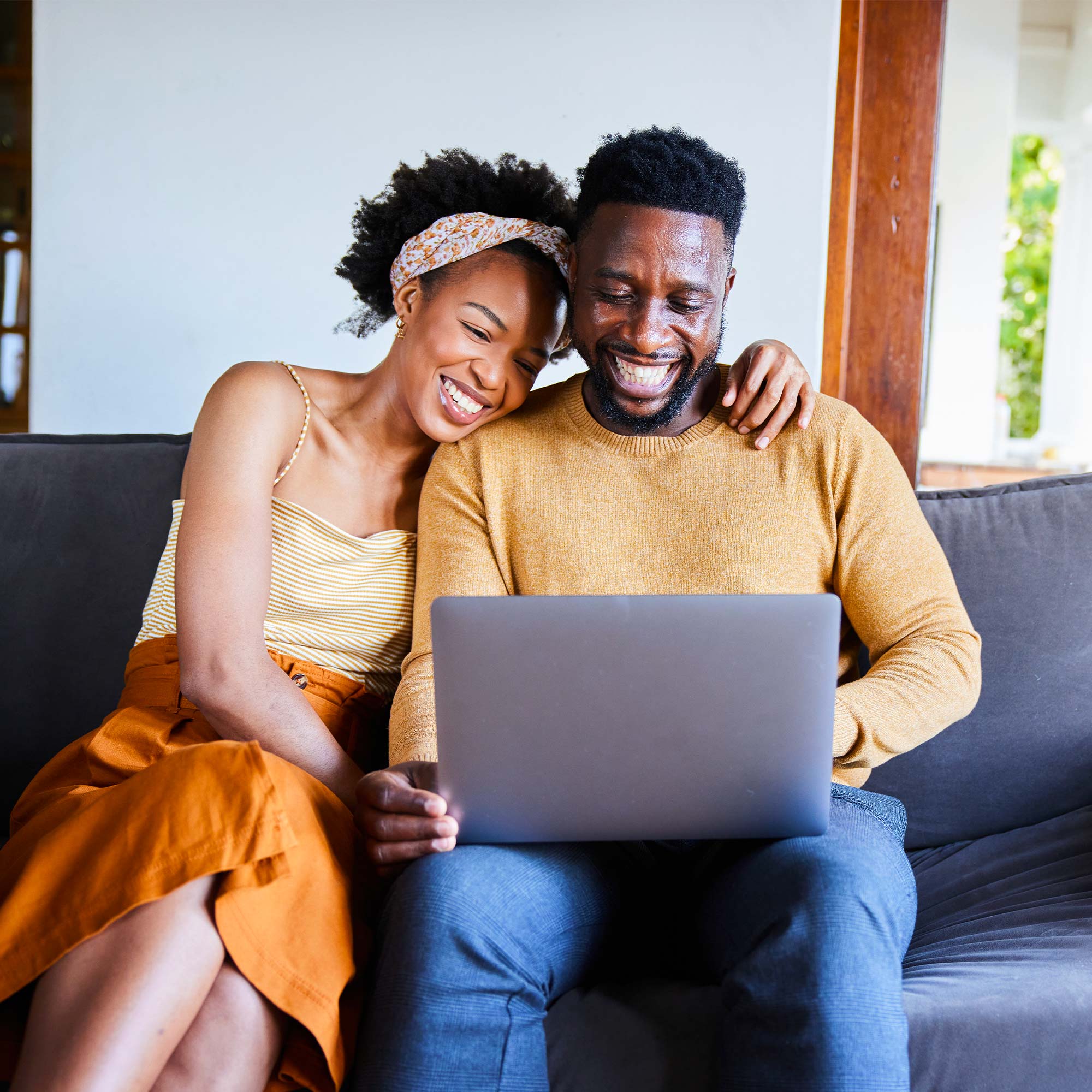 Two elders sitting outside looking at each other as they smile.