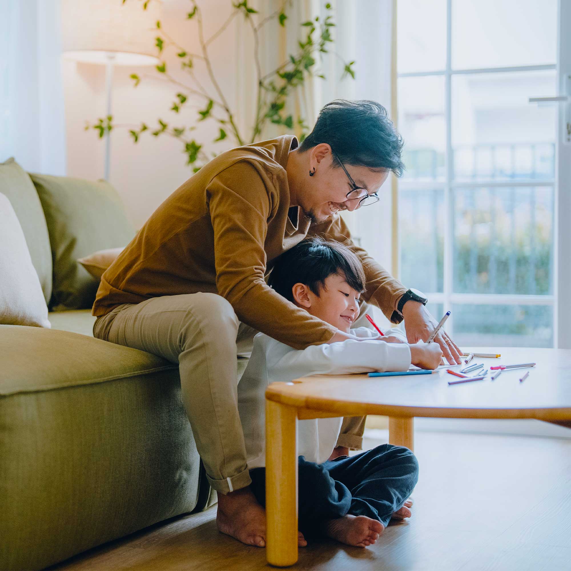 a woman and a boy sitting on a couch drawing