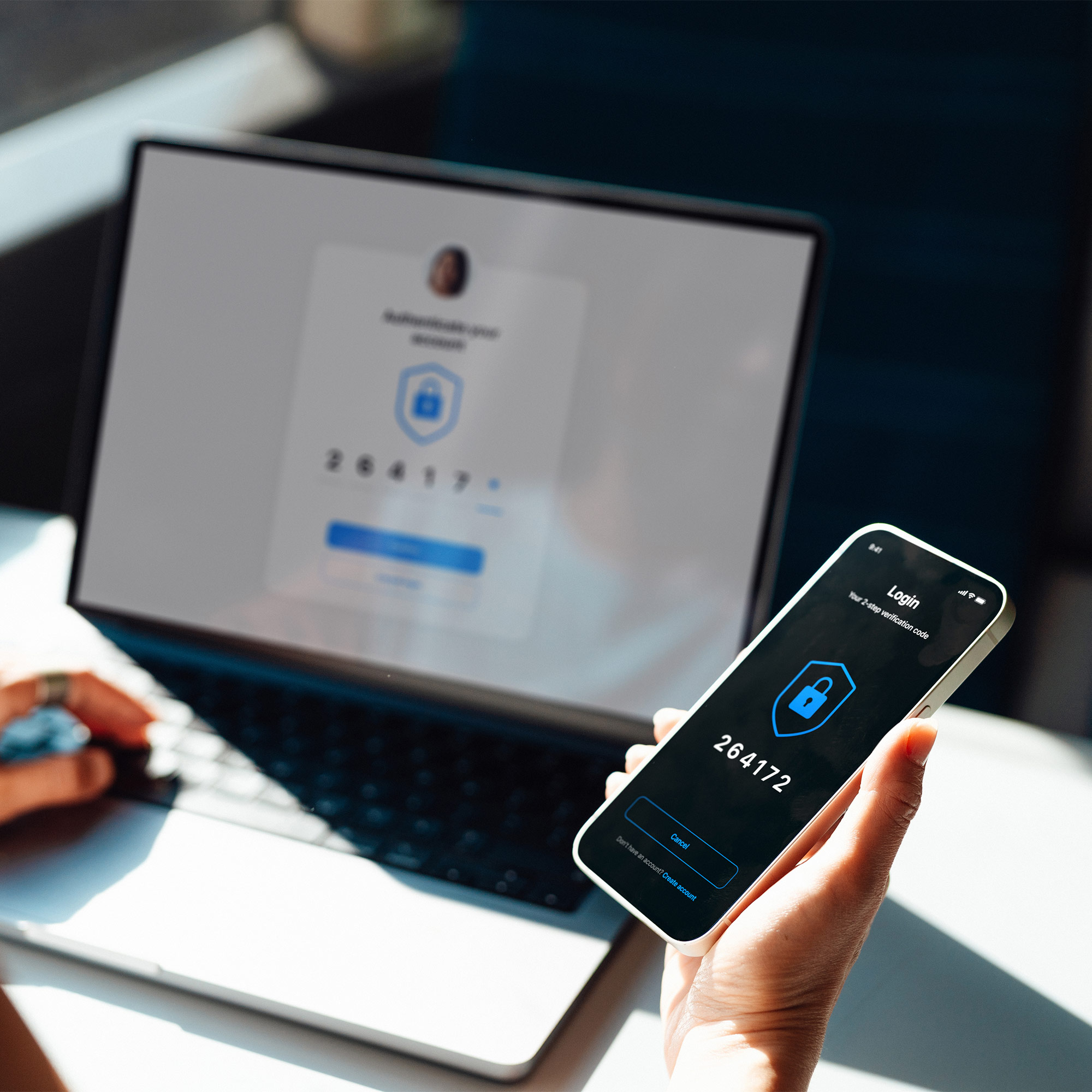 a person holding a phone in front of a laptop