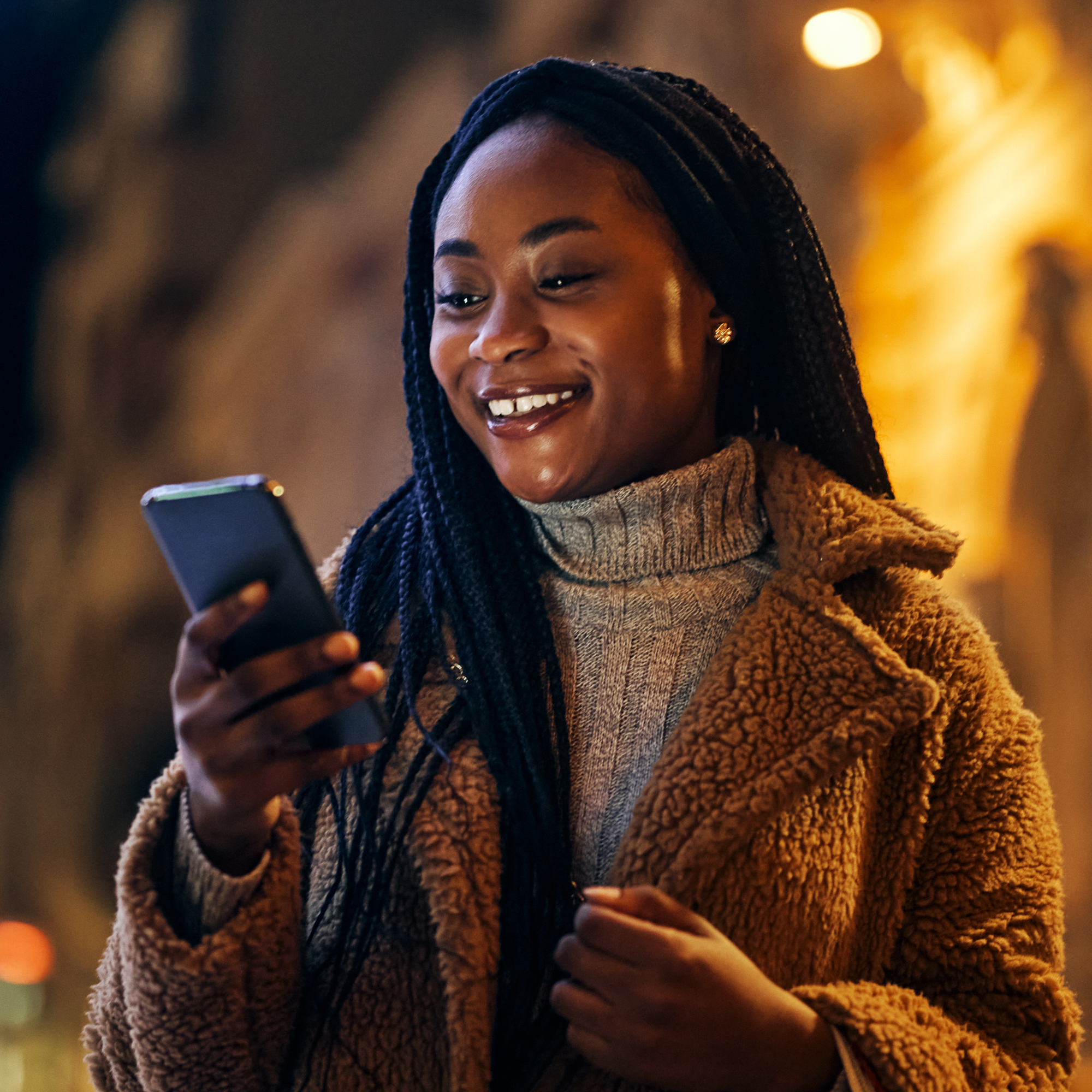 a woman smiling while looking at a phone