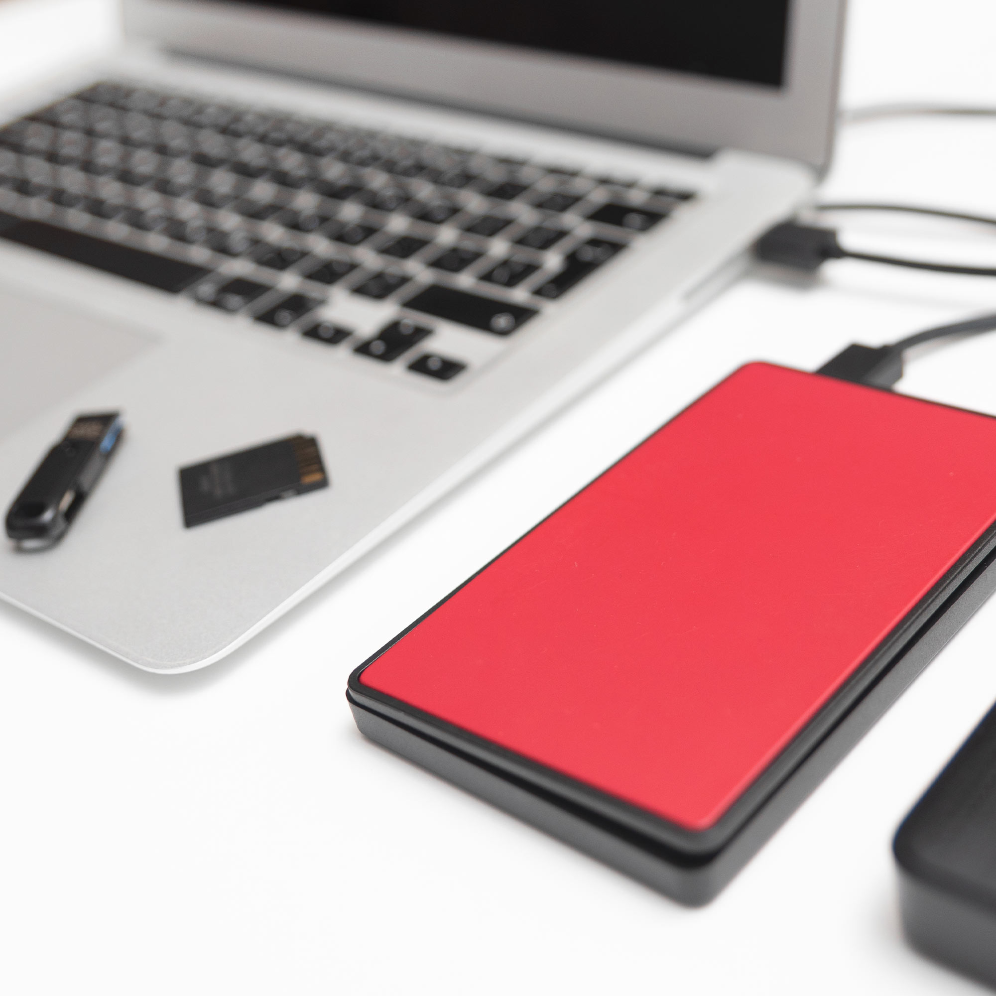 a red rectangular device next to a silver laptop