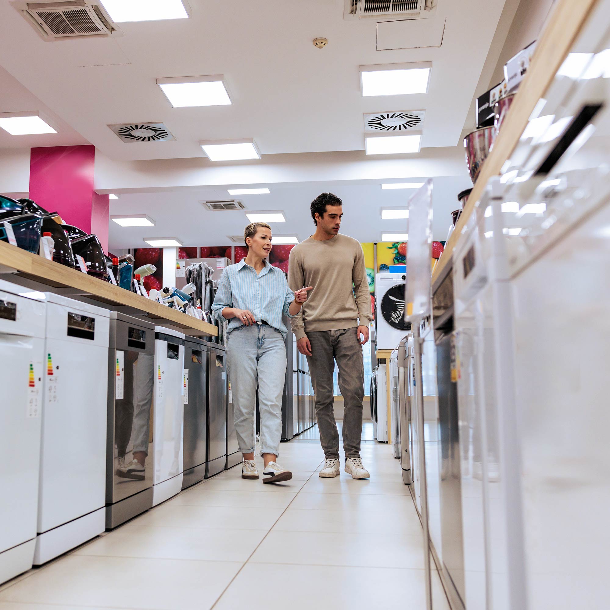 Two men walking and looking at appliances.