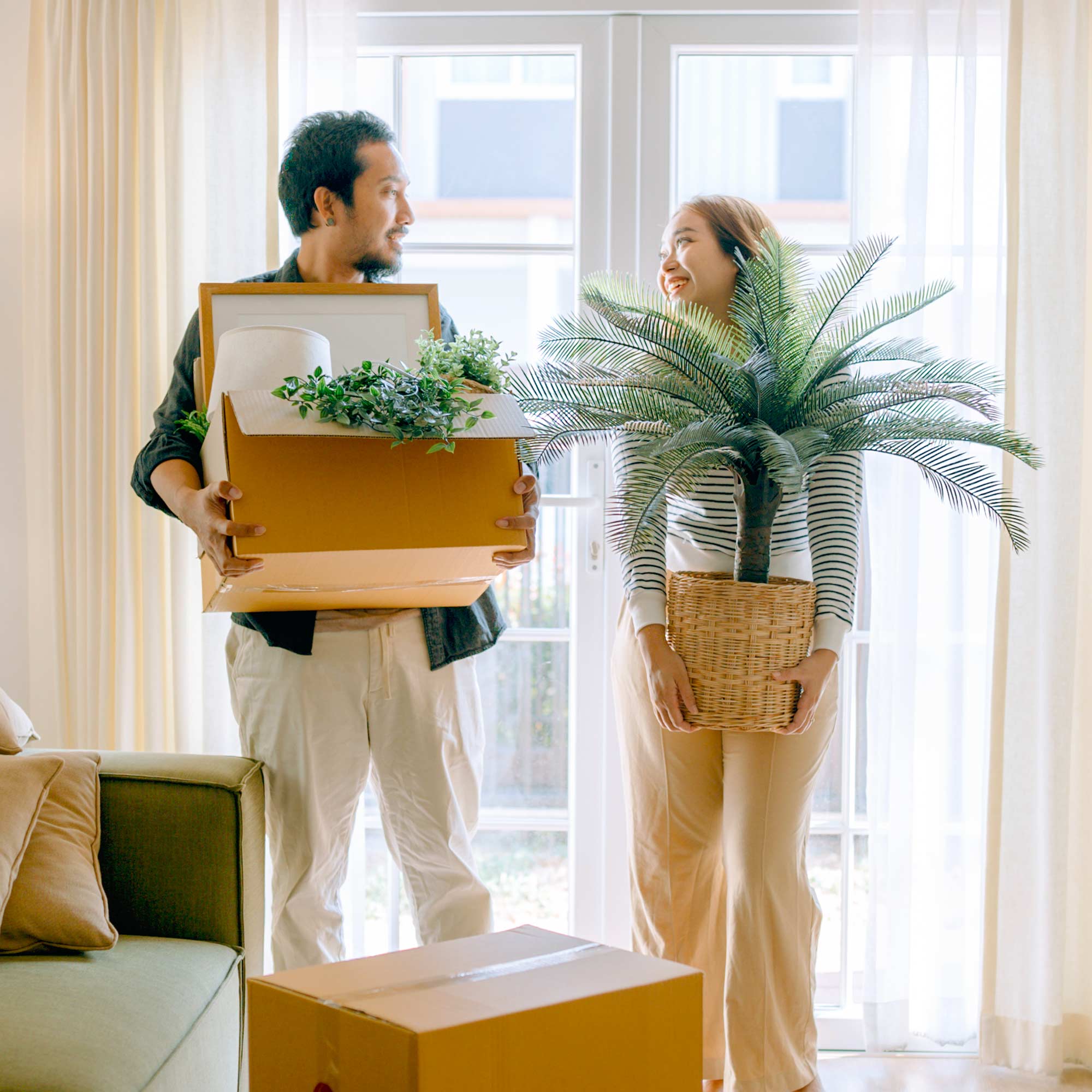 A man and a woman sit on the floor next to a pile of cardboard boxes.