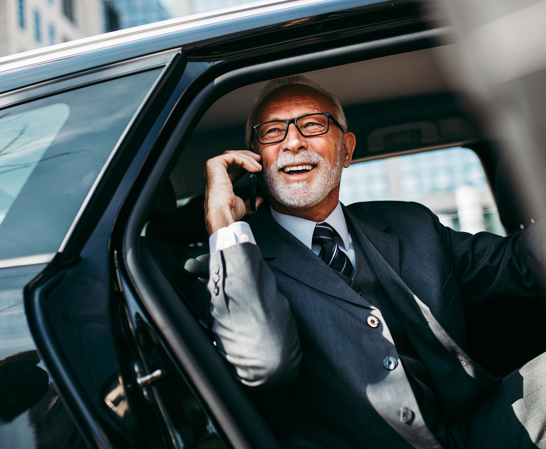 A businessman sitting in the back of a car using a phone